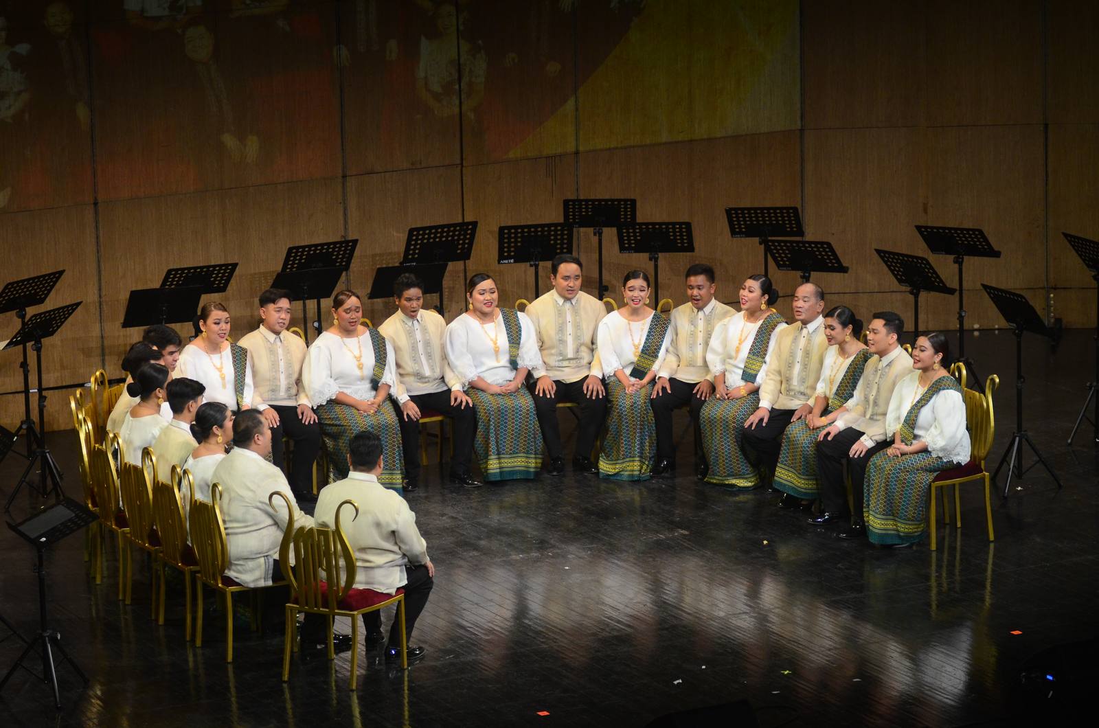 The Madz seated in their signature semi-circle on stage, singing without a conductor
